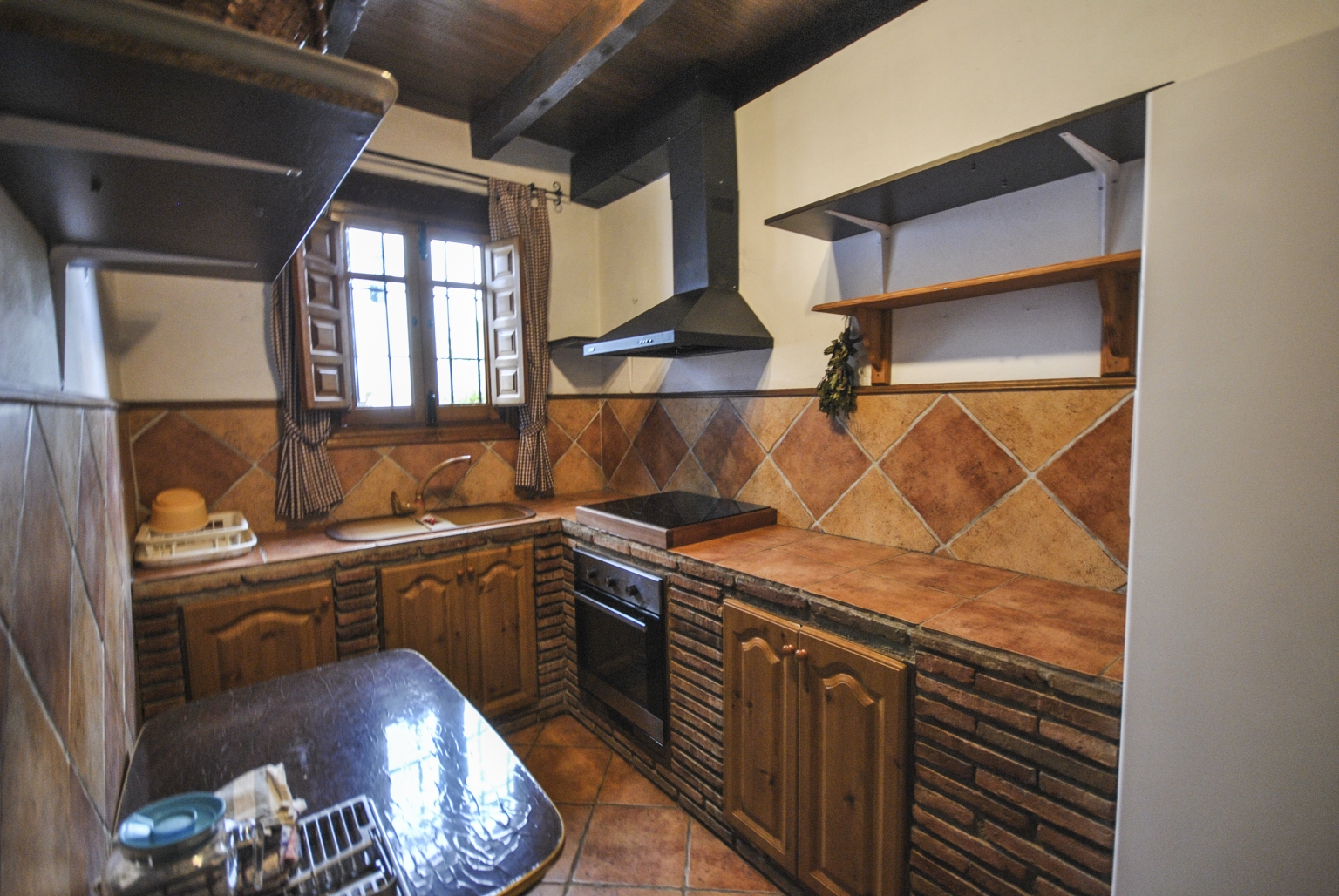 Salón comedor común con chimenea y pequeña cocina, para tus reuniones familiares o empresariales, en Cortijo Las Monjas. Un lugar acogedor en la Alta Axarquía, interior de la Costa del Sol, provincia de Málaga, Andalucía